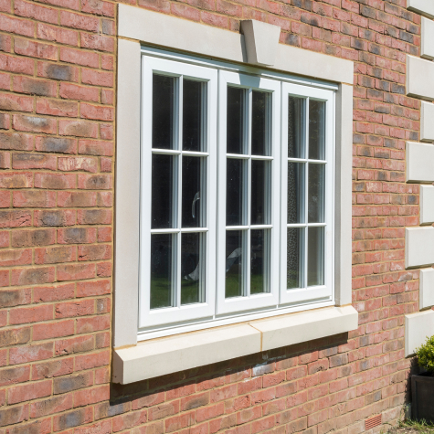 White casement windows with Georgian bars in a red-brick wall